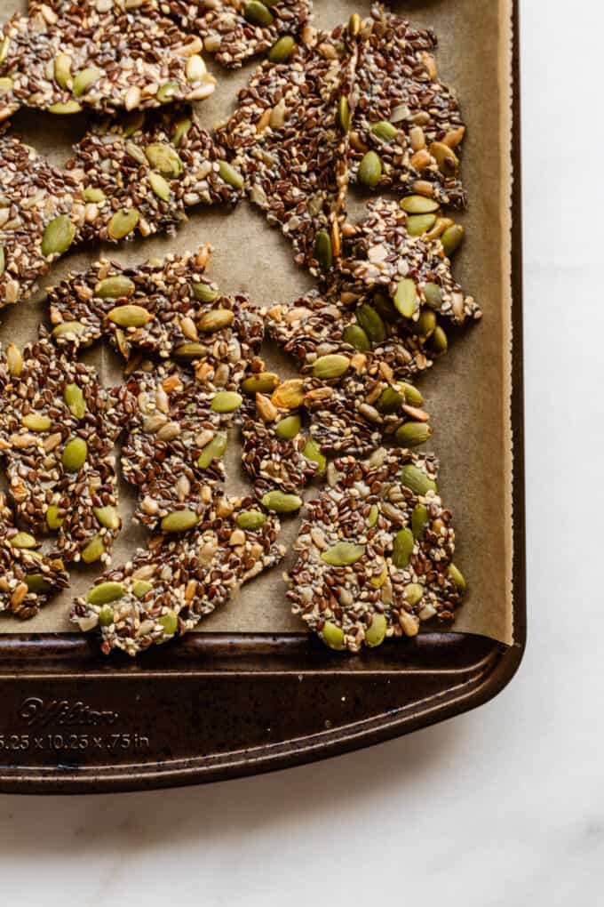 5 seed crackers broken into pieces on a baking sheet